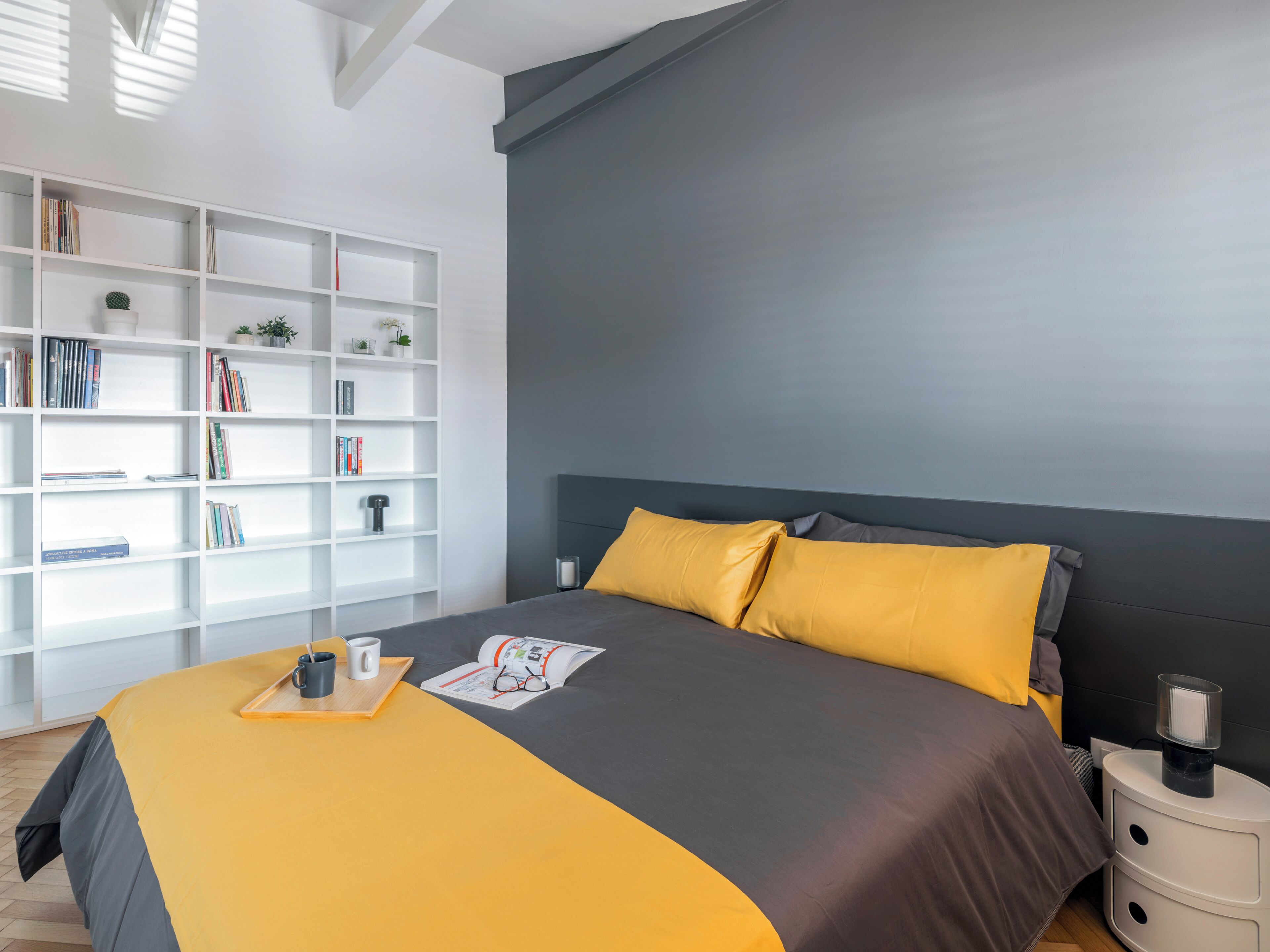 Une chambre à coucher moderne avec un lit, une bibliothèque et une table de chevet.