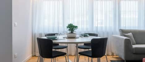 Un comedor moderno con una mesa redonda, cuatro sillas y un sofá al fondo.