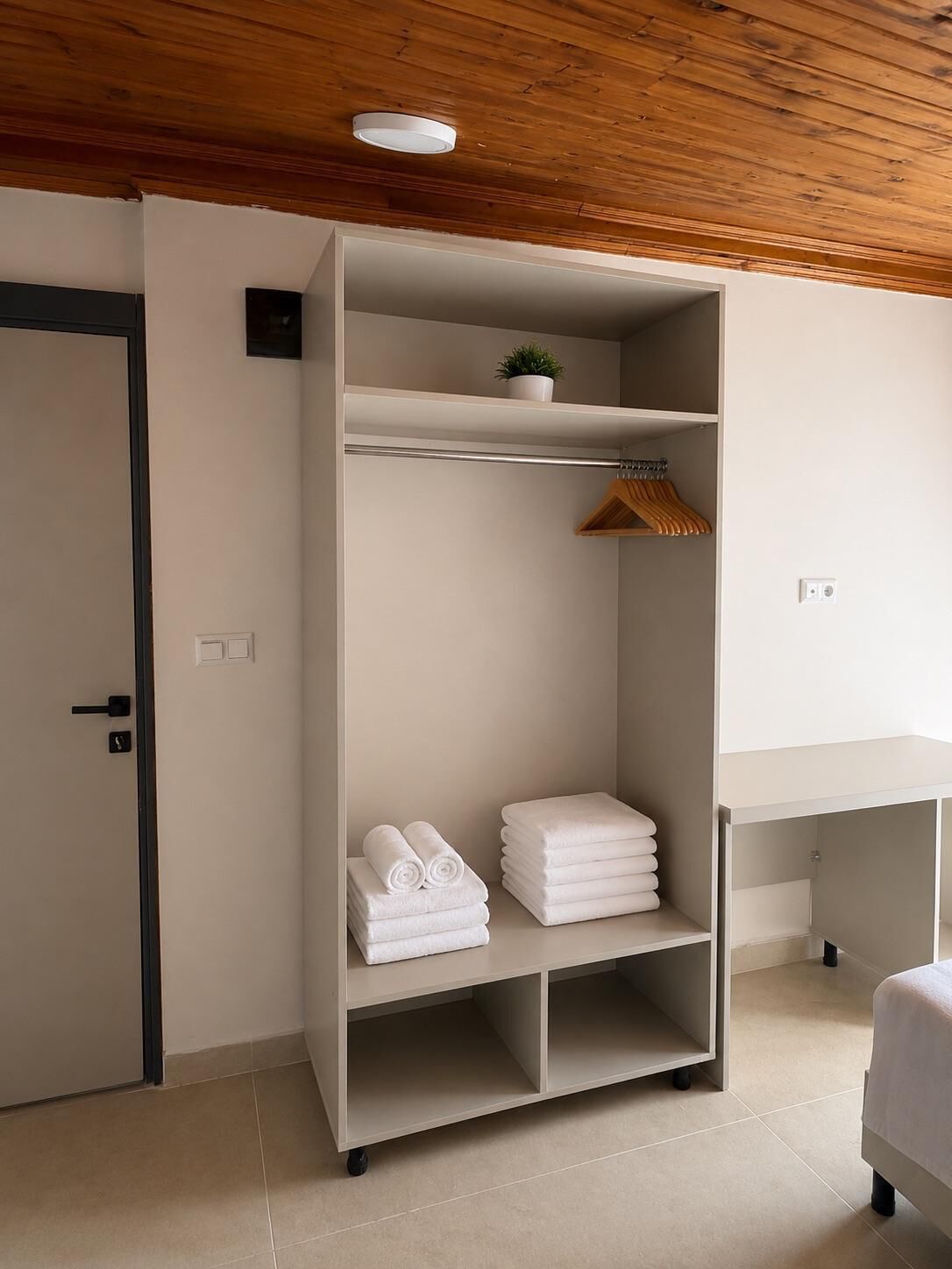 A hotel room with a wardrobe, a desk, and a bed.
