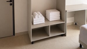 Quarto de hotel com guarda-roupa, escrivaninha e uma cama.