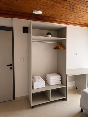 Una habitación de hotel con armario, escritorio y cama.