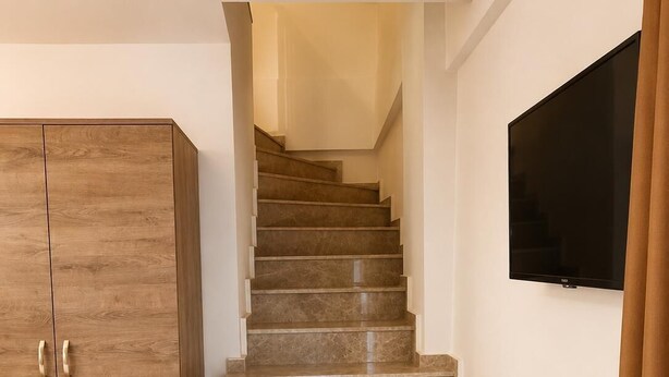 A staircase with a wooden wardrobe and a flat-screen TV on the wall.