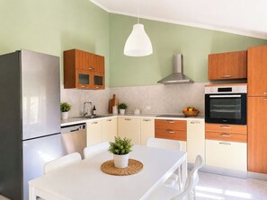 Eine moderne Küche mit Kühlschrank, Backofen und Holzschränken.