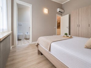 Makuuhuoneessa on sänky, yöpöytä, vaatekaappi ja kylpyhuone, joka näkyy avoimesta ovesta.