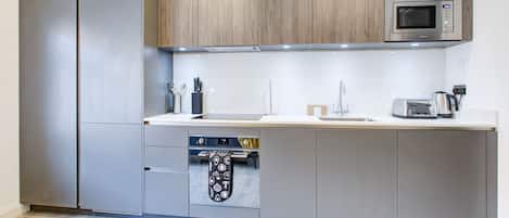 A modern kitchen with stainless steel appliances, wooden cabinets, and a built-in oven.