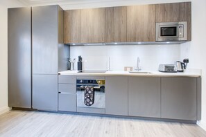 Eine moderne Küche mit Edelstahlgeräten, Holzschränken und einem eingebauten Backofen.