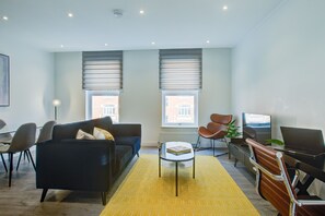 Un salon moderne avec un canapé, des fauteuils, une table basse, un téléviseur et un ordinateur portable.