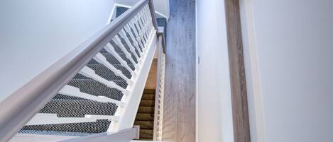 Una escalera con barandillas blancas y piso de madera.