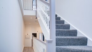 A staircase with a white railing and patterned carpet leading to an upper floor. - Hybrid Resi - Fulham - Three-Bedroom Apartment (London)