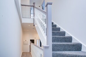Eine Treppe mit weißer Geländer und gemustertem Teppich, die zu einer oberen Etage führt.