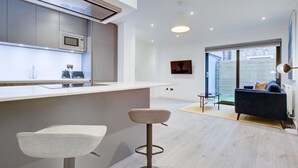 Eine moderne Küche mit integriertem Mikrowellenherd, einer Bar mit Hockern und einer Sitzecke mit Sofa und Tisch.