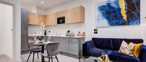 A modern living room with a dark blue sofa, a glass coffee table, and a contemporary abstract painting.