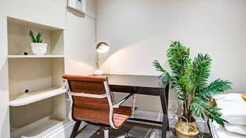 A workspace with a desk, chair, lamp, and potted plants.