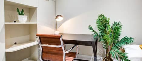 A workspace with a desk, chair, lamp, and potted plants.