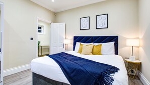 Un dormitorio con una cama grande, lámparas de noche y una puerta que da al baño.