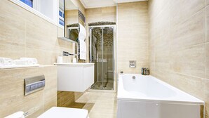 Un baño moderno con bañera, inodoro y zona de ducha.