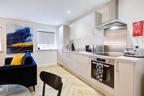 A modern kitchen with white cabinets, stainless steel appliances, and a herringbone floor pattern.