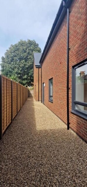A pathway leading to a brick building with a window and a door.