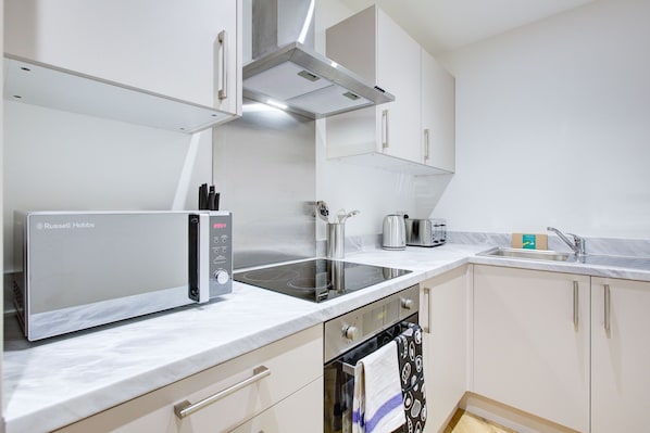 A modern kitchen with a built-in oven, a microwave, and a stovetop.