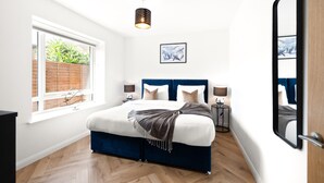 A bedroom with a bed, bedside lamps, a window, and a wall-mounted artwork. - Hybrid Resi - Mitcham - Two-Bedroom Apartment (Mitcham)