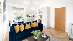 A modern living room with a dark blue sofa, a coffee table, and a potted plant. - Hybrid Resi - Mitcham - Two-Bedroom Apartment (Mitcham)