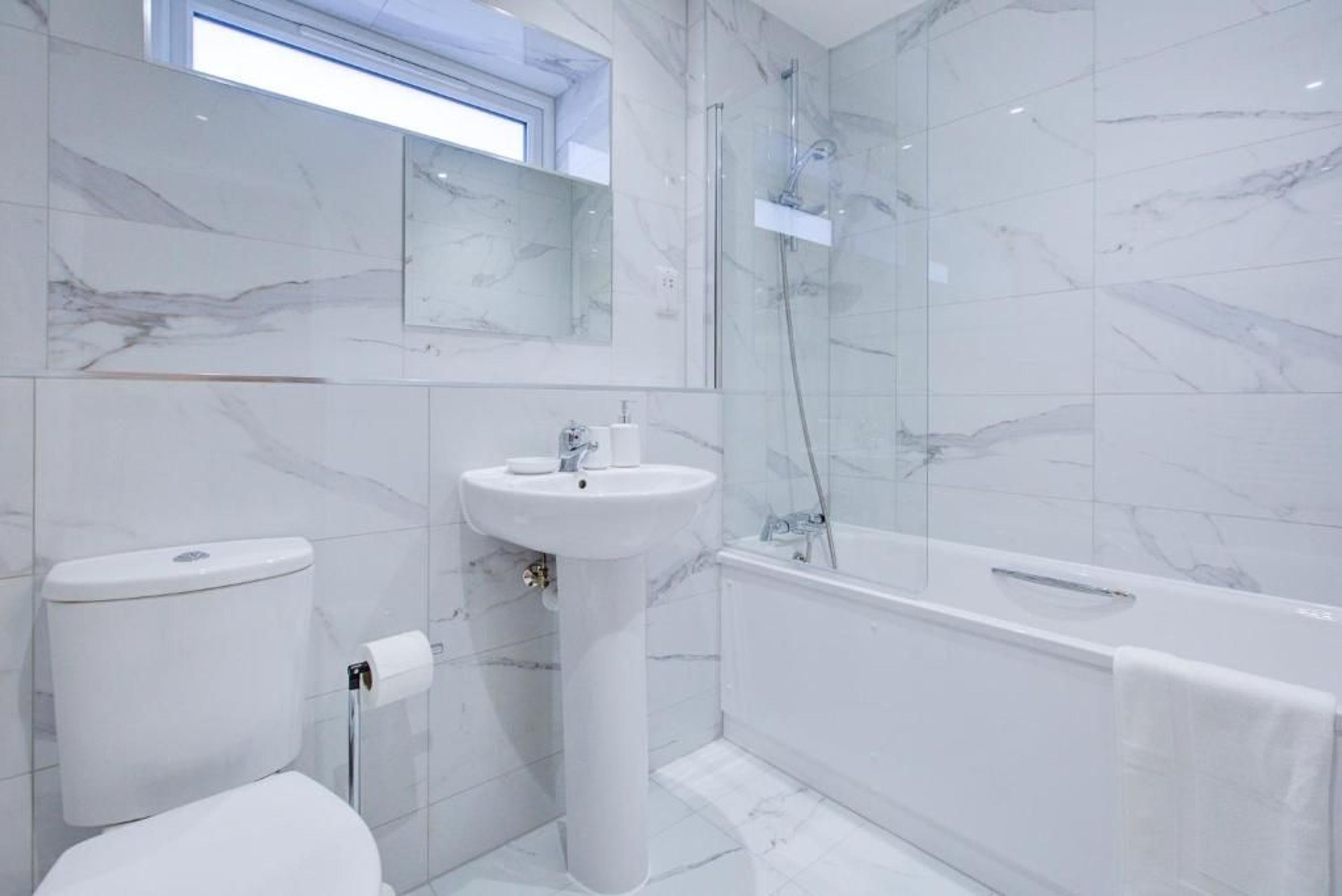 A modern bathroom with a toilet, sink, and shower.