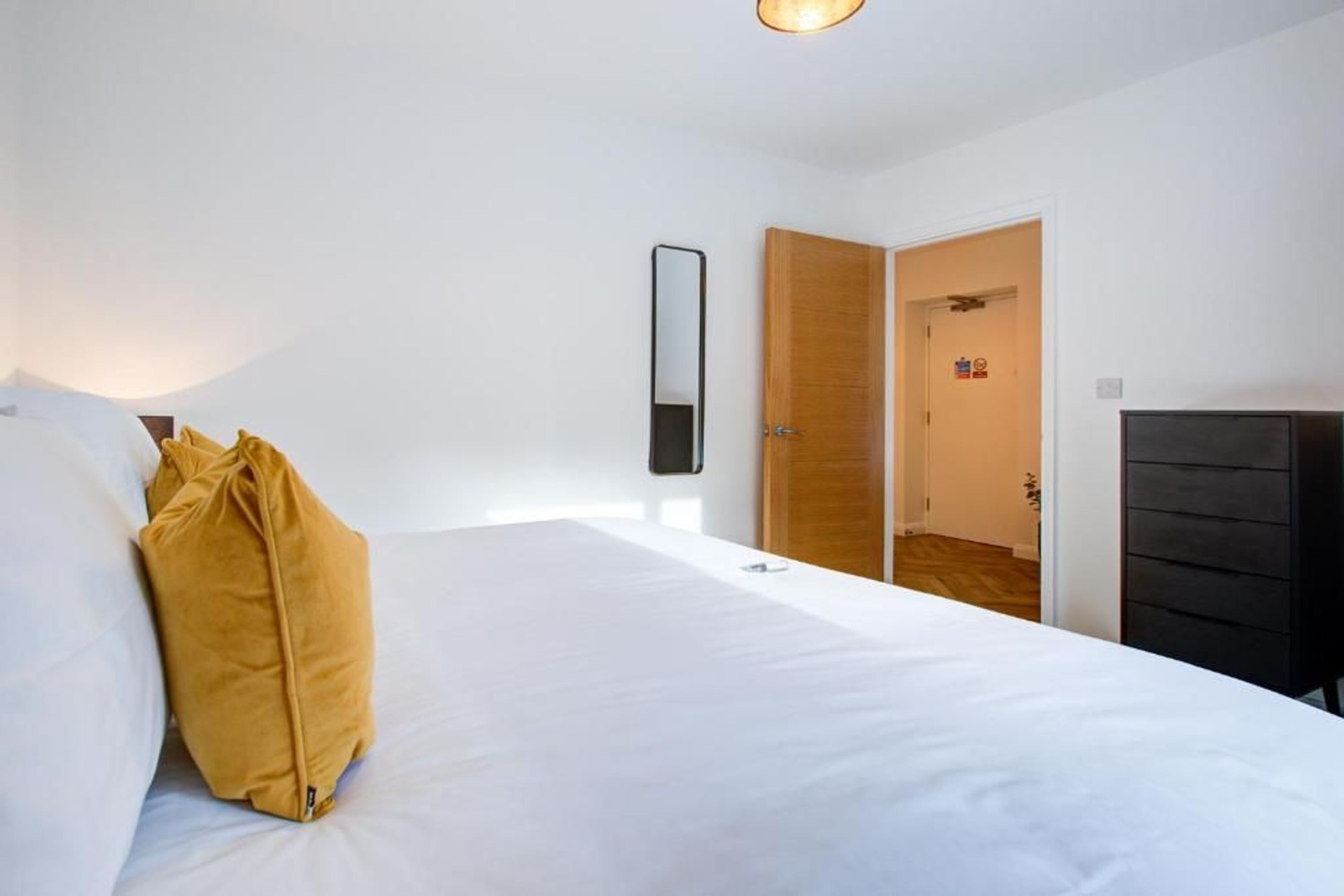 Une chambre à coucher avec un lit, une armoire en bois, une porte et un miroir fixé au mur.