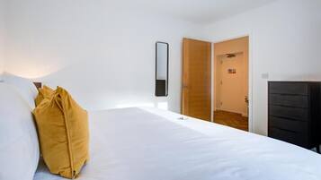 Une chambre à coucher avec un lit, une armoire en bois, une porte et un miroir fixé au mur.