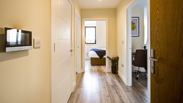 Un couloir avec un lit, un bureau et une chaise dans une pièce.