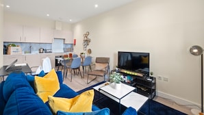 Un salon moderne avec un canapé, un téléviseur et un coin repas.