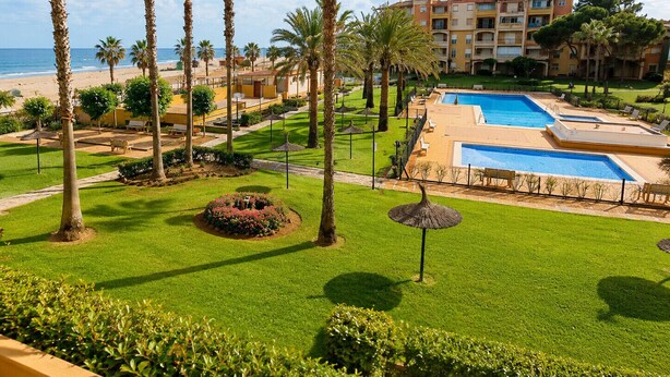 A resort with multiple swimming pools, palm trees, and a beachfront view. - Alcaraván T2, Sea view apartment - Ref. 11P21 (Ayamonte)
