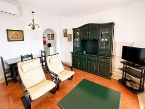 A living room with a dining table, two chairs, a television, and a green cabinet. - Alcaraván T2, Sea view apartment - Ref. 11P21 (Ayamonte)