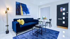 Una sala de estar moderna con un sofá azul, una mesa de centro y un cuadro en la pared.