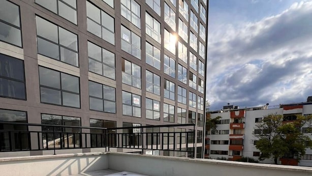 Una terraza en la azotea con un jacuzzi, un edificio moderno al fondo y cielo despejado.