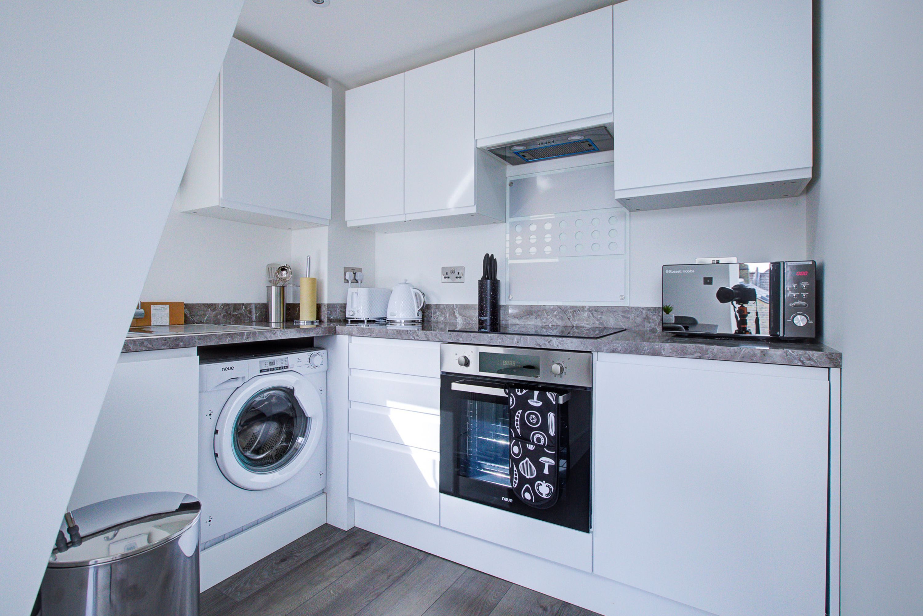 A compact kitchen with a washing machine, dishwasher, and a small refrigerator.