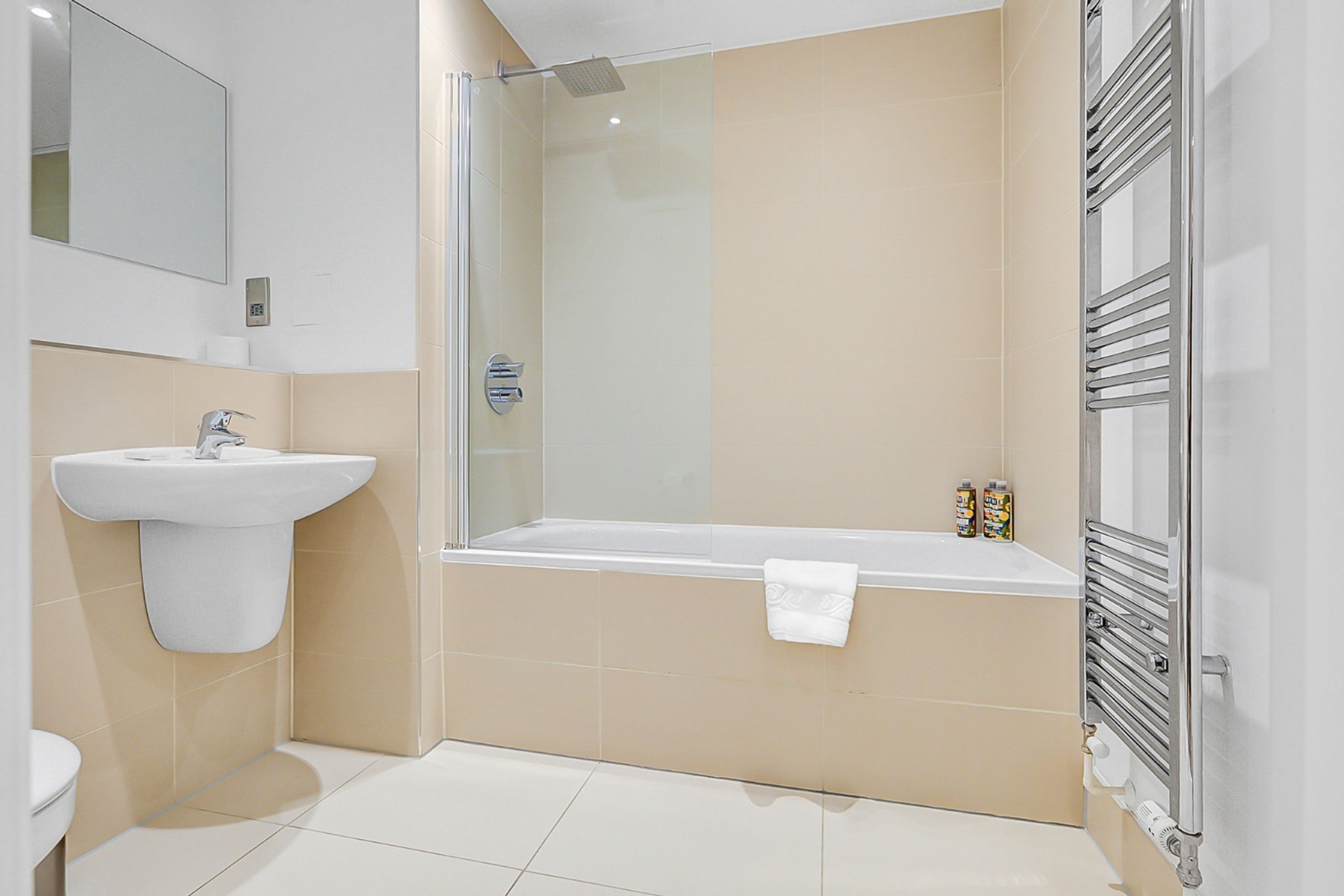 Un baño moderno con ducha de vidrio, un lavamanos blanco y una bañera.