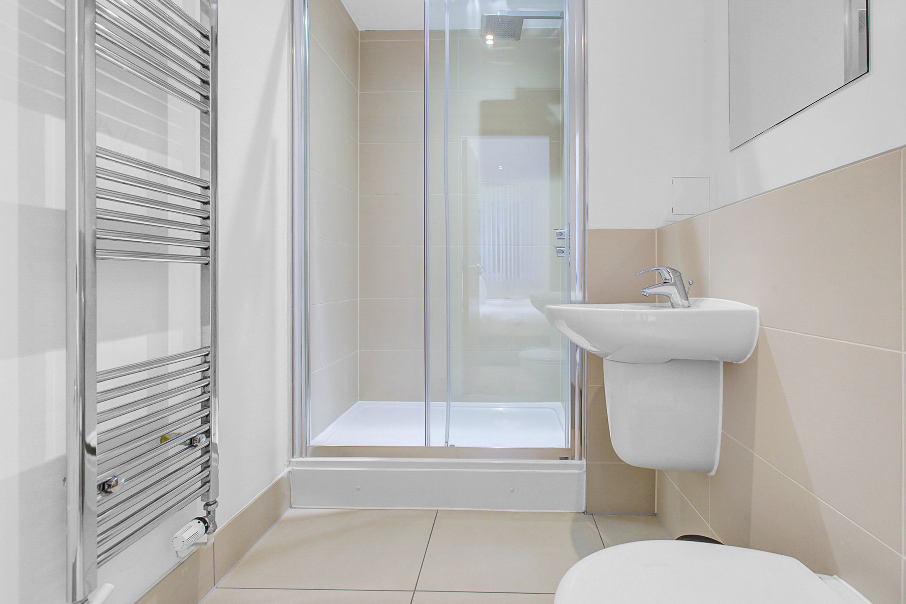 A modern bathroom with a glass-enclosed shower, a white sink, and a toilet.