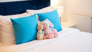 Ein Bett mit zwei Kissen, einem blauen und einem weißen, und zwei Stofftieren darauf.