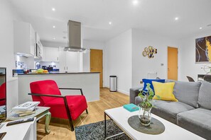 Un salon moderne avec un fauteuil rouge, un canapé gris et une petite table basse.