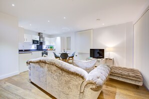 Una sala de estar moderna con un sofá, un televisor y un comedor con una mesa y sillas.