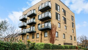 Un immeuble résidentiel à plusieurs étages, doté de balcons et d’une façade en briques, avec un ciel dégagé.