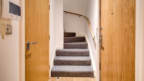 Un escalier en bois, dont les marches sont recouvertes de moquette, mène à un palier.