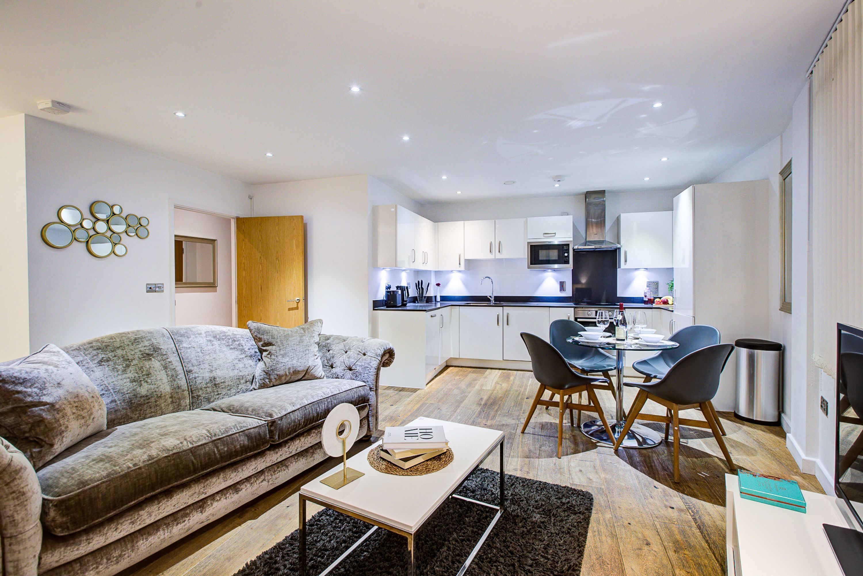 A modern living room with a sofa, a coffee table, and a dining area with chairs and a table.
