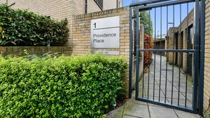 Une entrée fermée par un portail mène à un immeuble sur lequel est apposée une plaque indiquant « 1, Providence Place ».