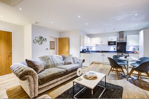 Ein modernes Wohnzimmer mit einer Couch, einem Couchtisch und einem Essbereich mit Stühlen und einem Tisch.