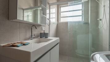Un baño moderno con un espejo grande, un lavamanos y una zona de ducha.