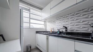 A modern kitchen with white cabinets, a black countertop, and a patterned backsplash. - StayHome Ponta da Praia - 2min da Praia (Santos)