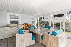A covered outdoor seating area with wicker furniture and a glass-top table.