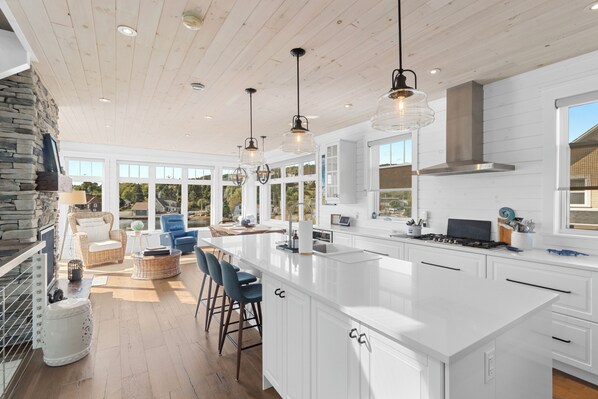 A spacious kitchen with a large island, white cabinetry, and pendant lighting.
