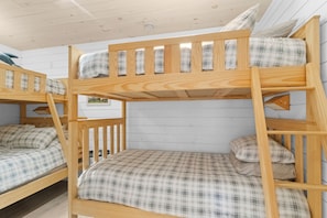 A bunk bed room with a white wall and a wooden ceiling.
